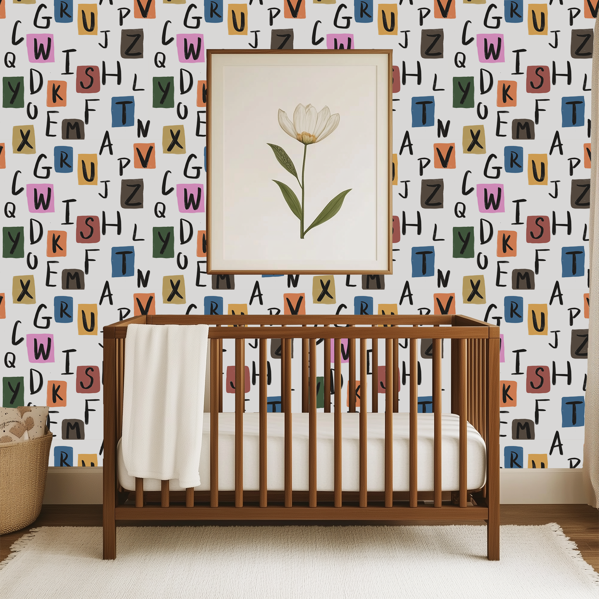 Colorful alphabet wallpaper behind wooden crib, modern nursery wallpaper with hand drawn letters and learning theme