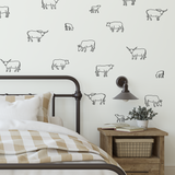 Black outline cow decals on white wall in rustic bedroom with checkered bedding