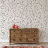 Wooden dresser with red vases against a simple line floral wallpapered wall.