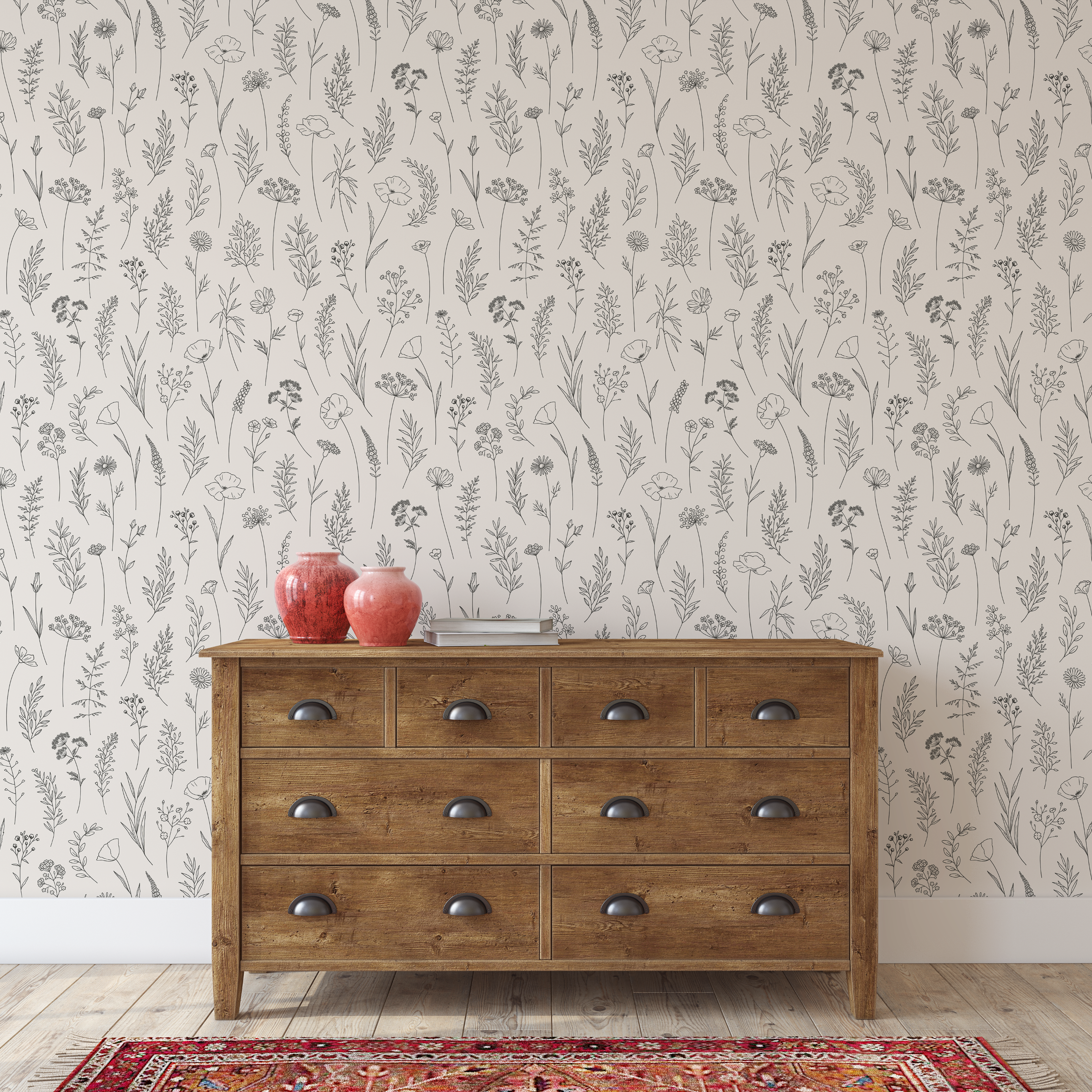 Wooden dresser with red vases against a simple line floral wallpapered wall.