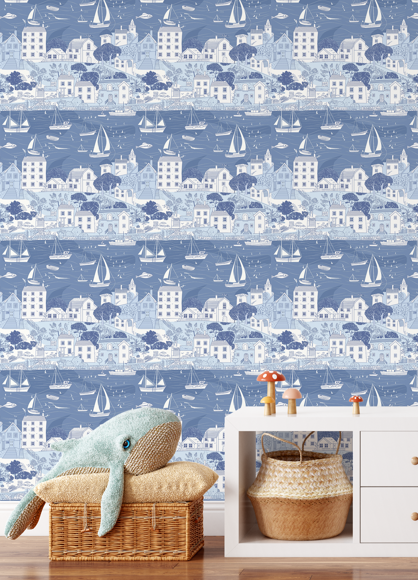 Seaside sailboat wallpaper in blue tones styled in kids playroom with wicker basket and plush whale