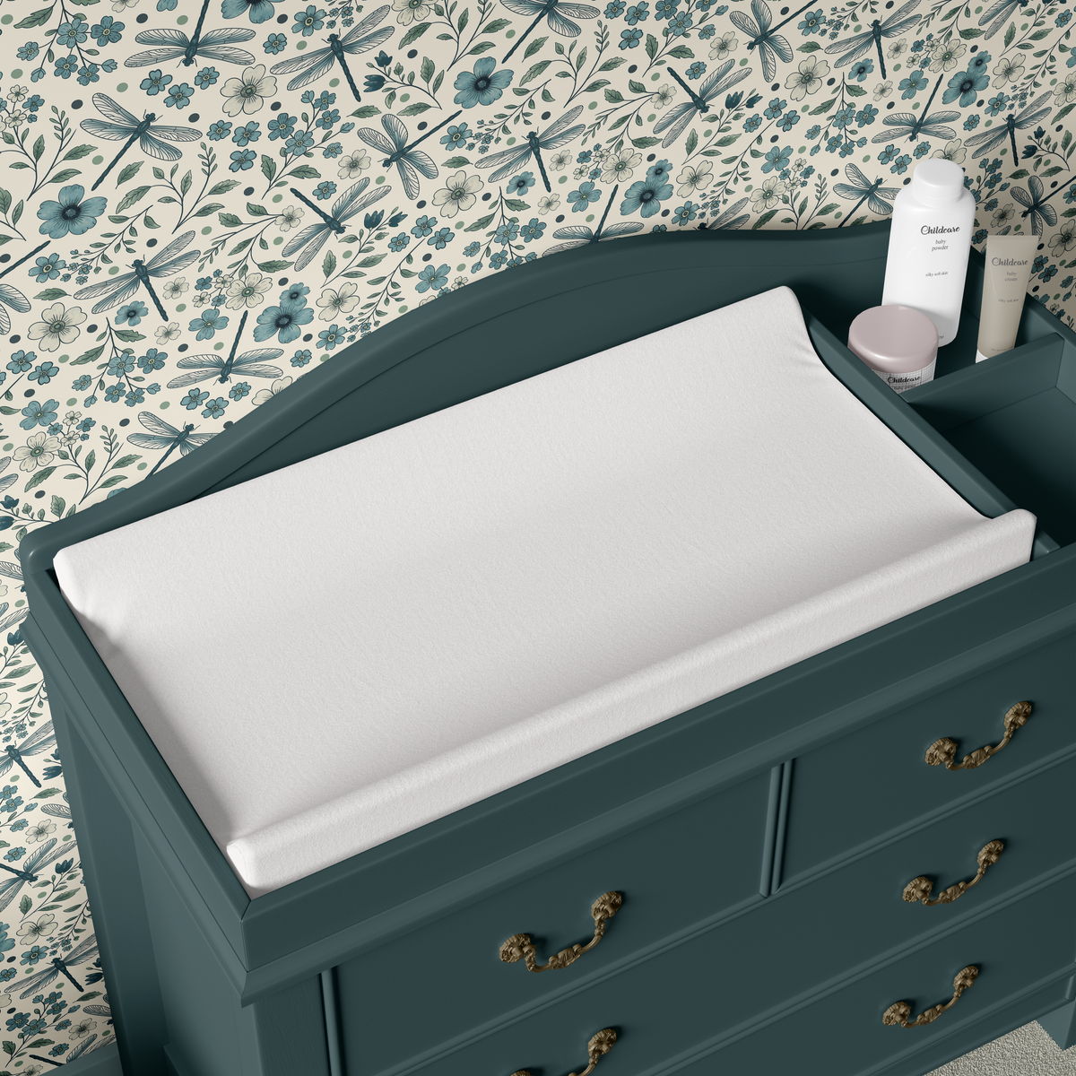 Blue dragonfly and floral wallpaper styled in a nursery with a deep teal changing table and warm brass hardware.