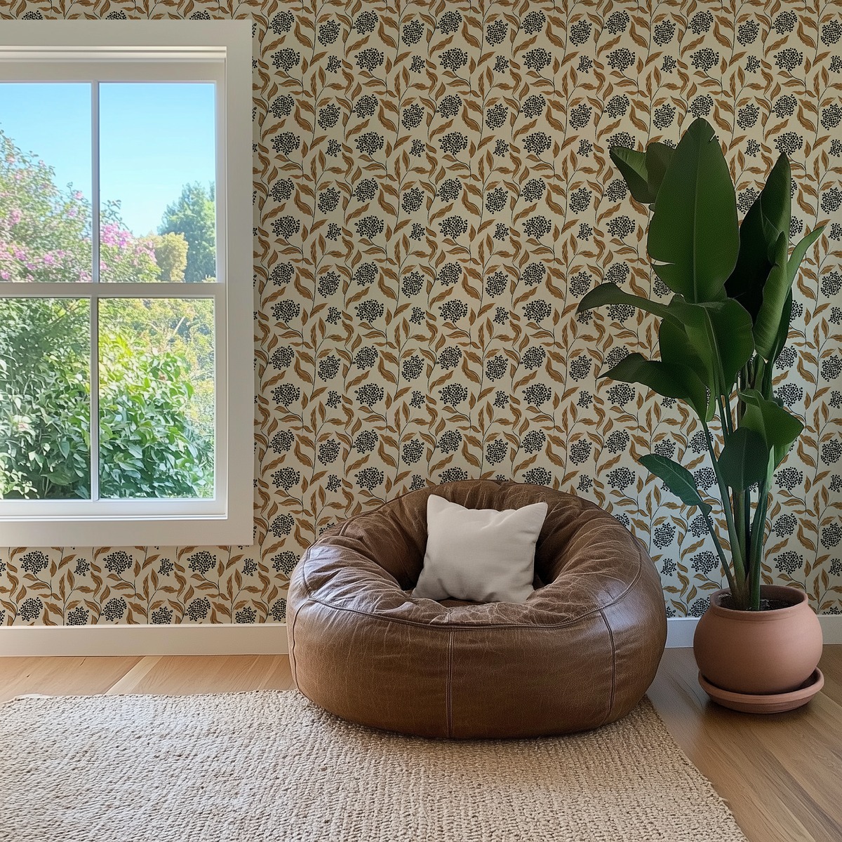 Elderberry Grove neutral floral wallpaper styled in a warm living room with brown leather chair and large green houseplant.