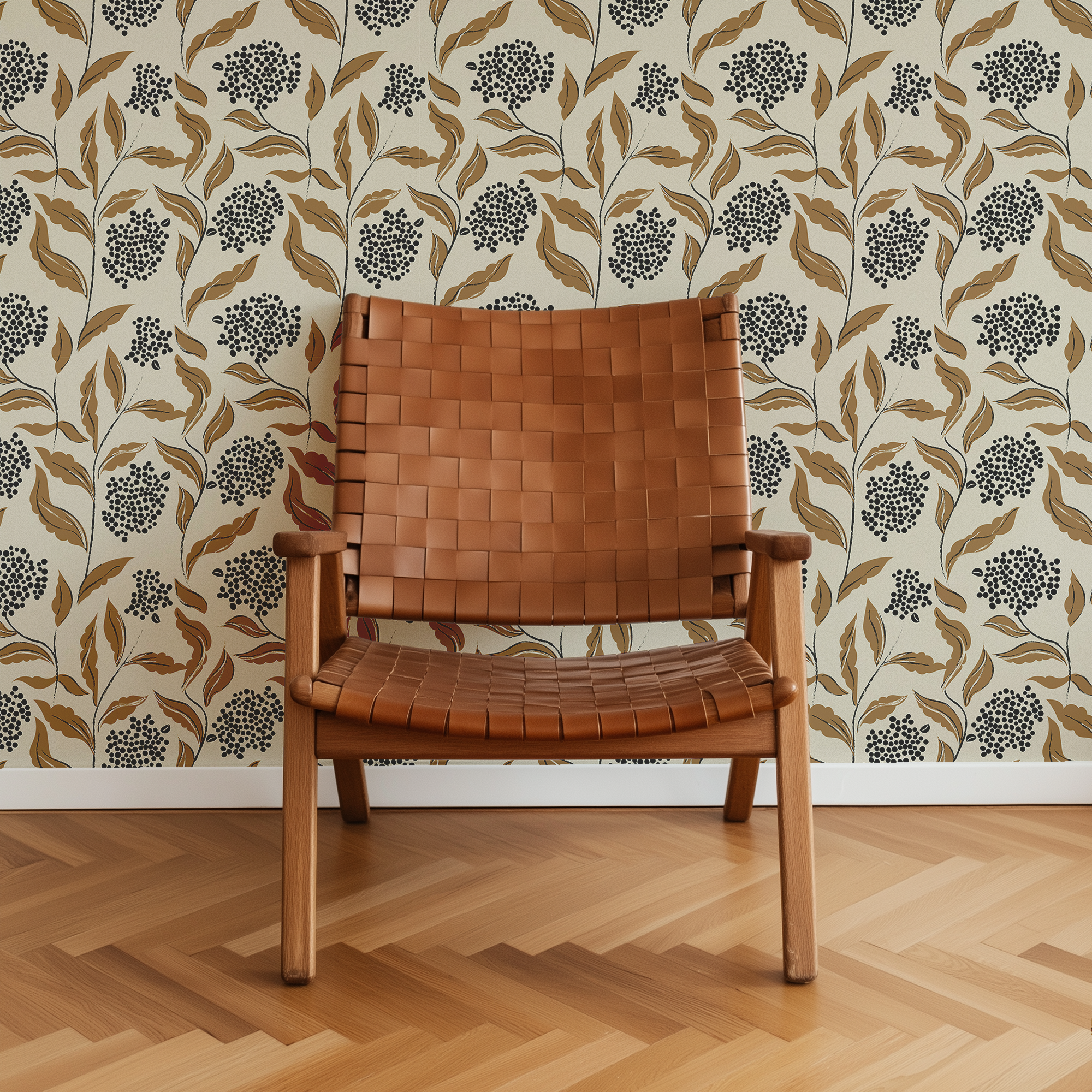 Elderberry Grove brown and black floral wallpaper with cream background styled behind a warm brown leather woven chair.