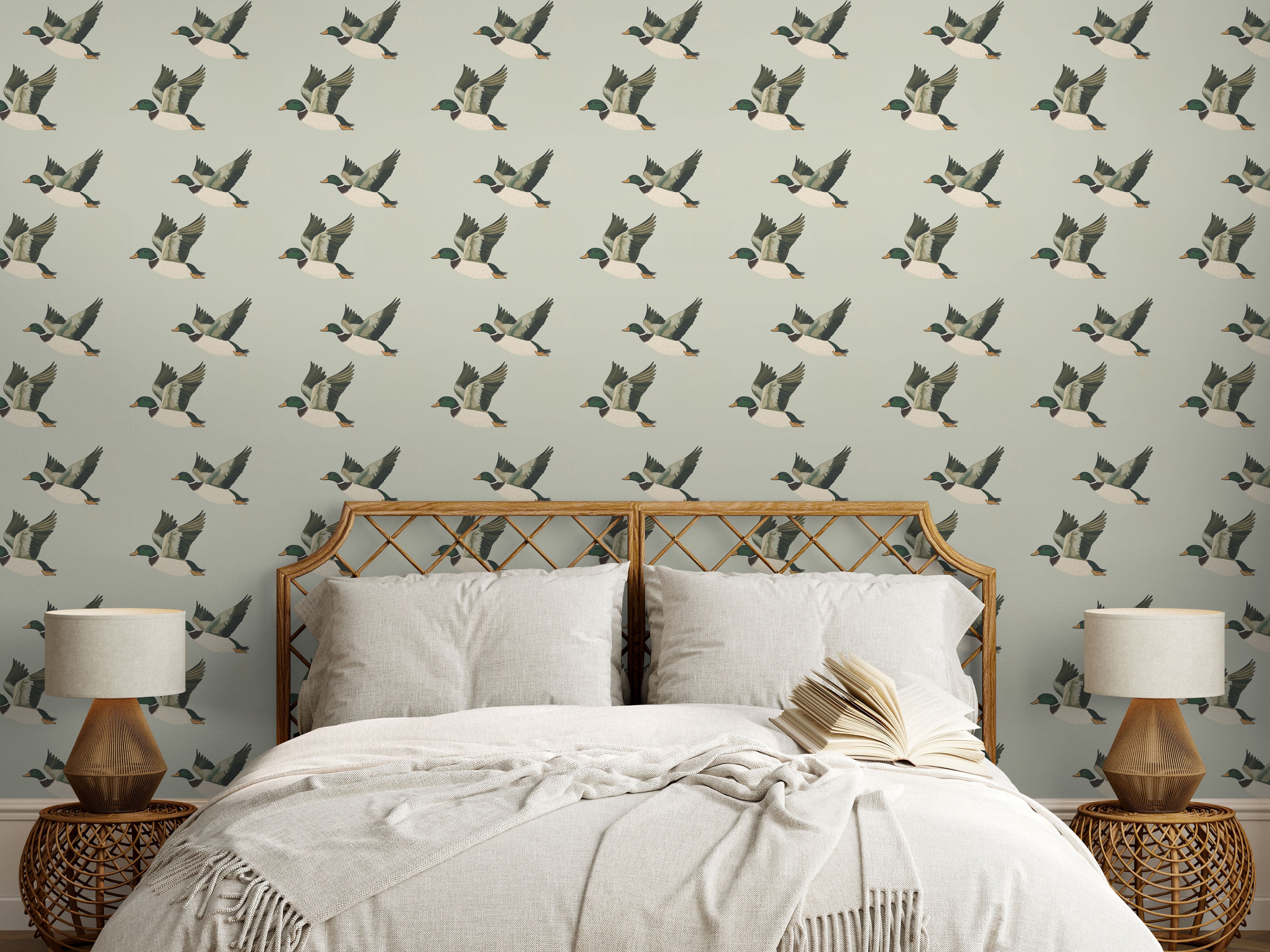 Bedroom with flying duck wallpaper behind rattan headboard and neutral bedding