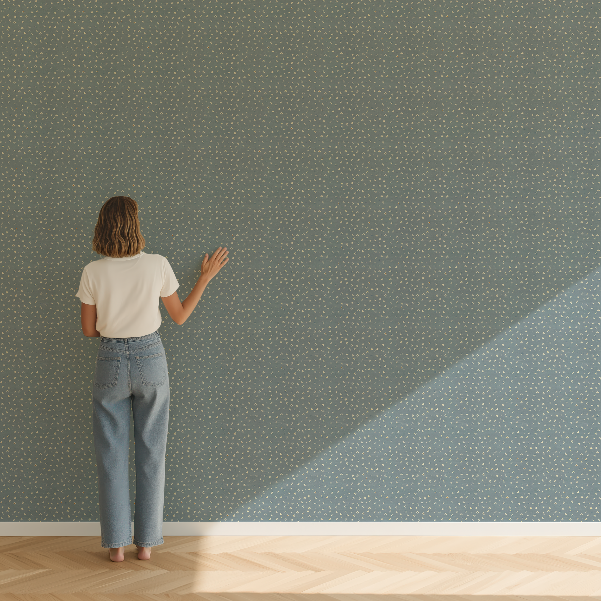 A woman stands with her back to the camera against a sage green wall covered in a small white floral dotted pattern, with light casting a diagonal shadow on the floor.