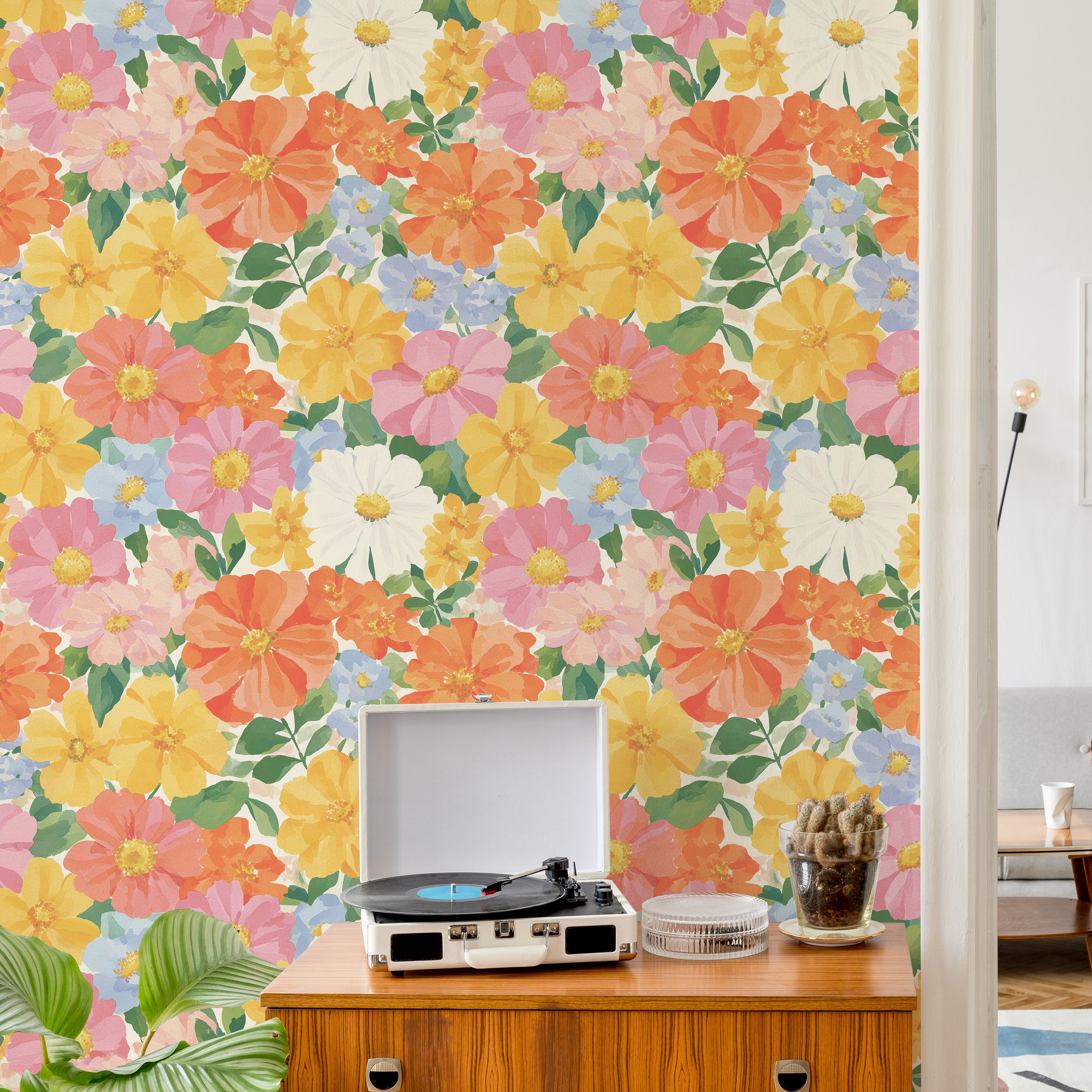 Bright watercolor floral wallpaper in pink, coral, yellow and blue behind mid century console with record player