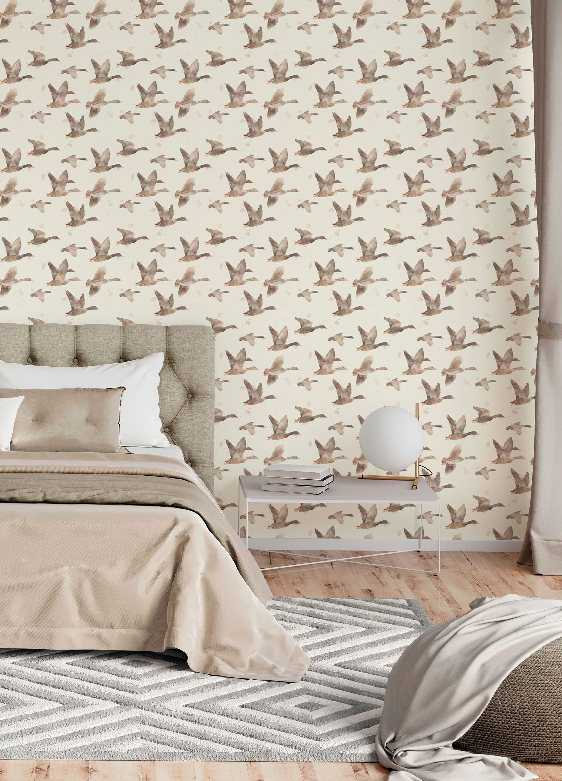 Bedroom with neutral flying geese wallpaper behind tufted headboard and beige bedding