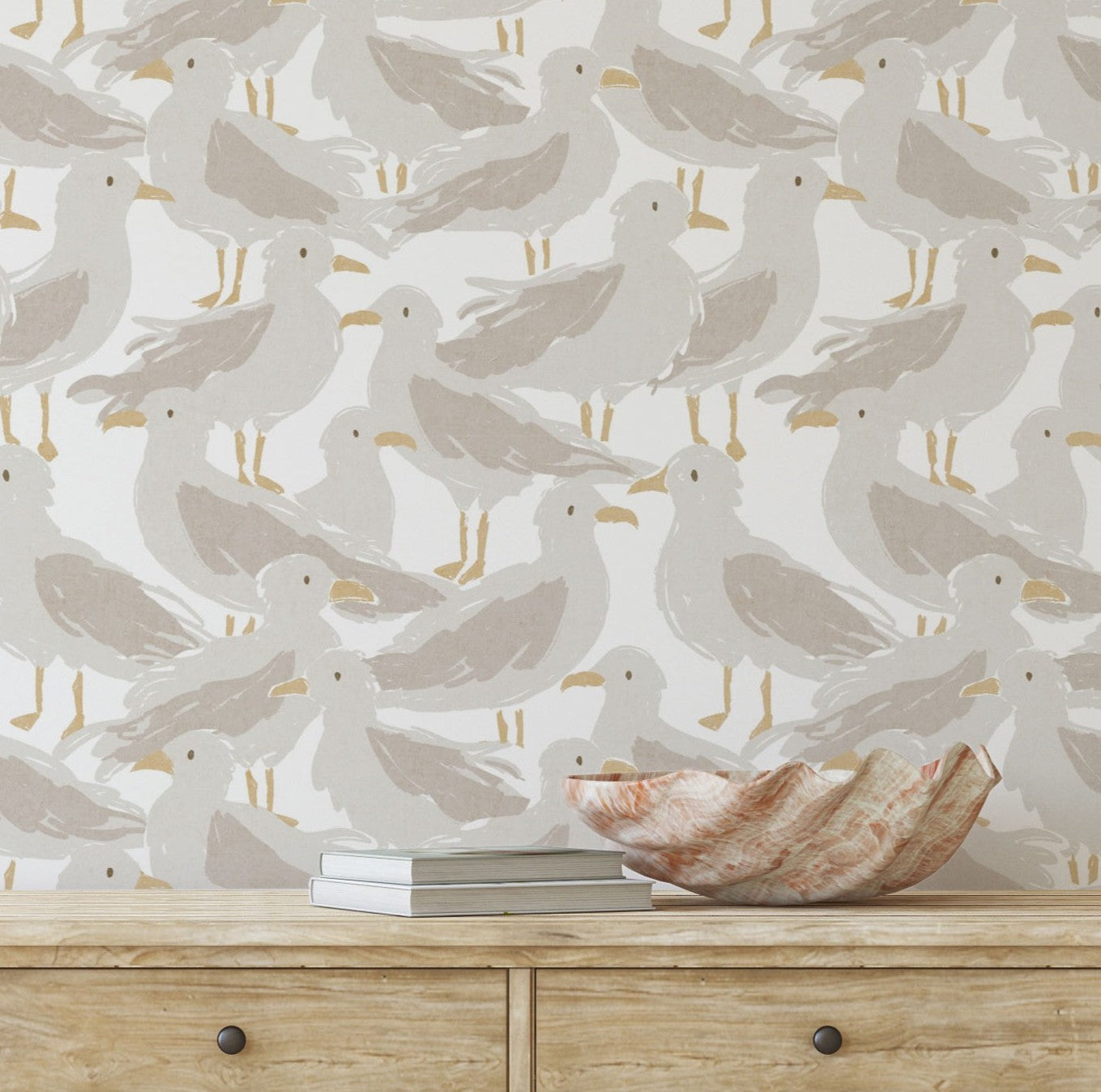 Wallpaper with seagull pattern on a wall behind a wooden dresser with decorative items.