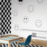 Black and white checkered kids room with large smiley face wall decals on white wall and wooden furniture