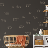 Cow decals in warm beige outline on dark nursery wall with rattan crib and shelves