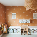 Spacious child's play area with a terracotta wall, white sunburst stickers, and educational charts, illuminated by natural light