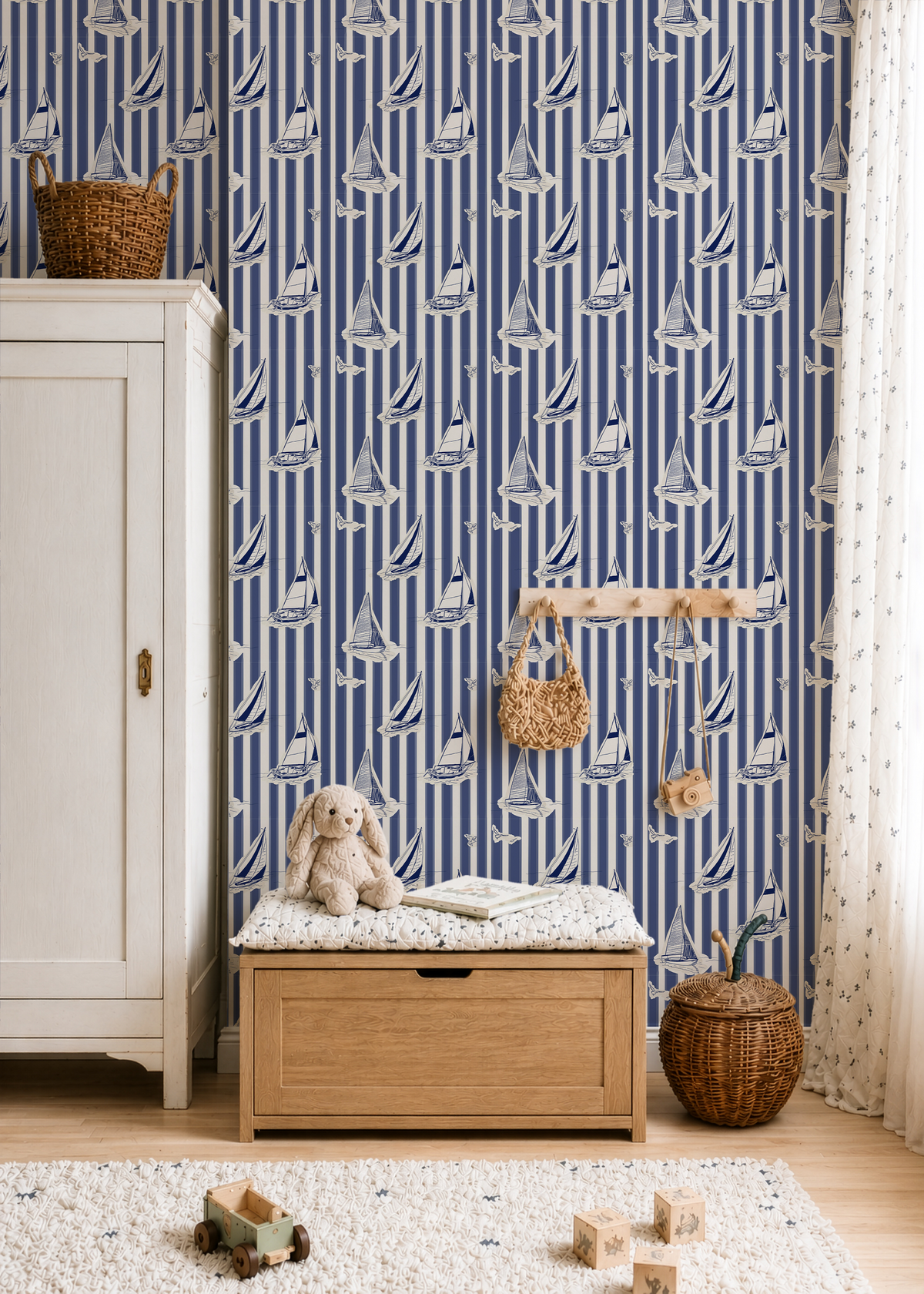 Nautical sailboat wallpaper styled in a coastal kids room with blue stripes, wood furniture and toy storage