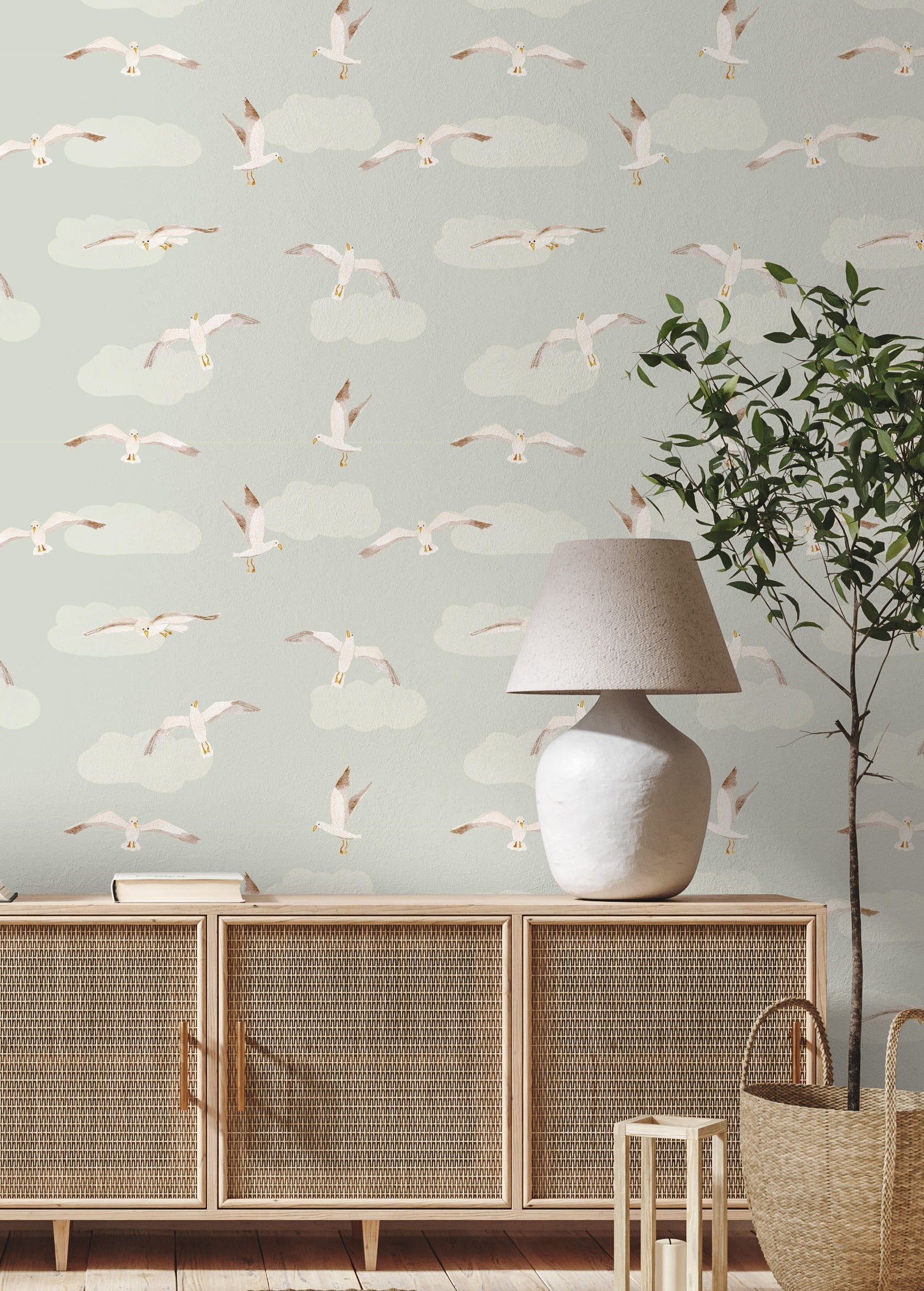 Room interior with a sideboard, lamp, and decorative wallpaper featuring flying seagulls.