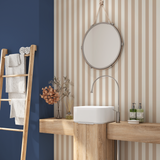 Sandstone beige and cream stripe wallpaper in a modern bathroom with wood vanity and round mirror