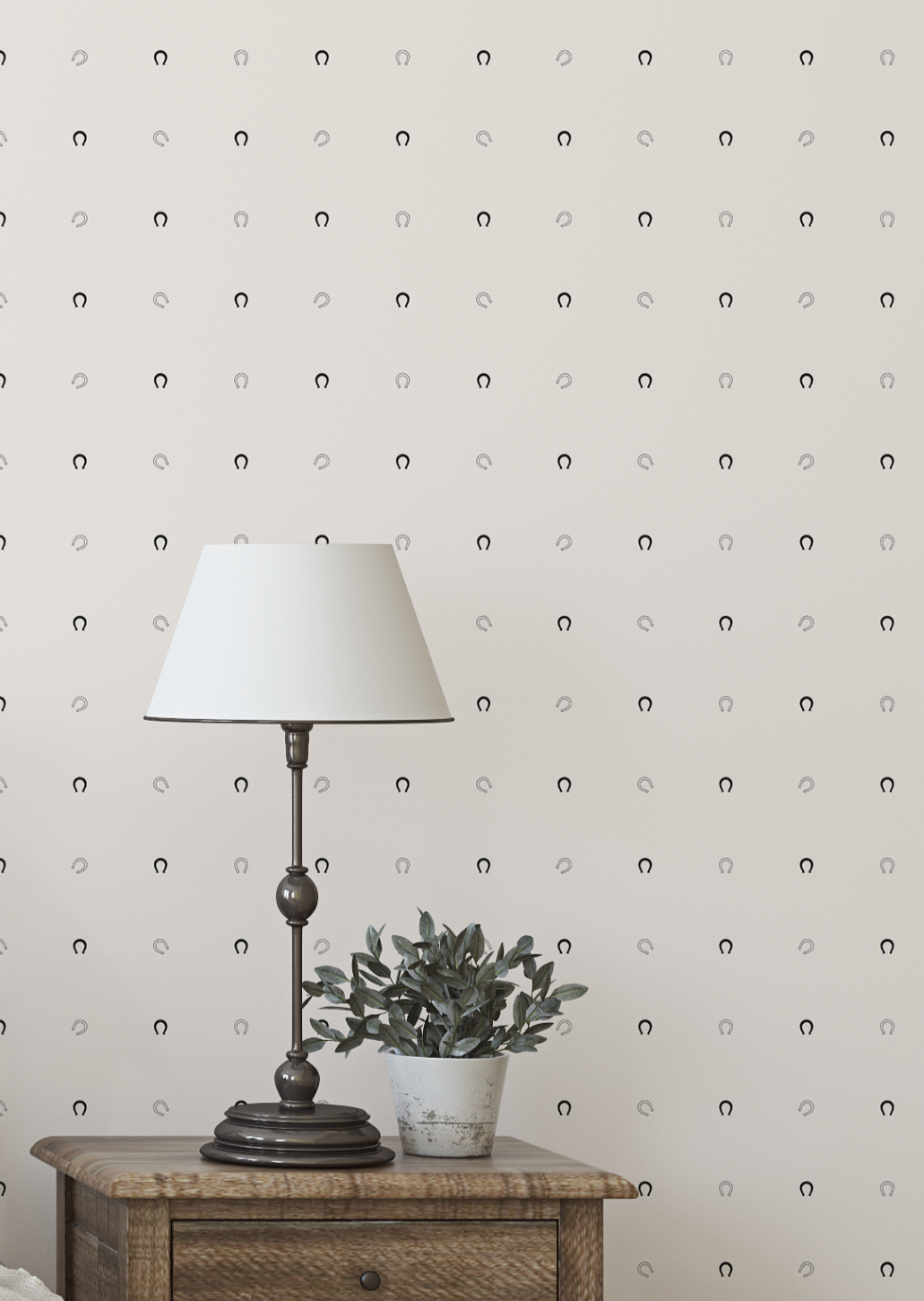 Wallpaper with a subtle horseshoe pattern, lamp, and plant on a wooden surface.