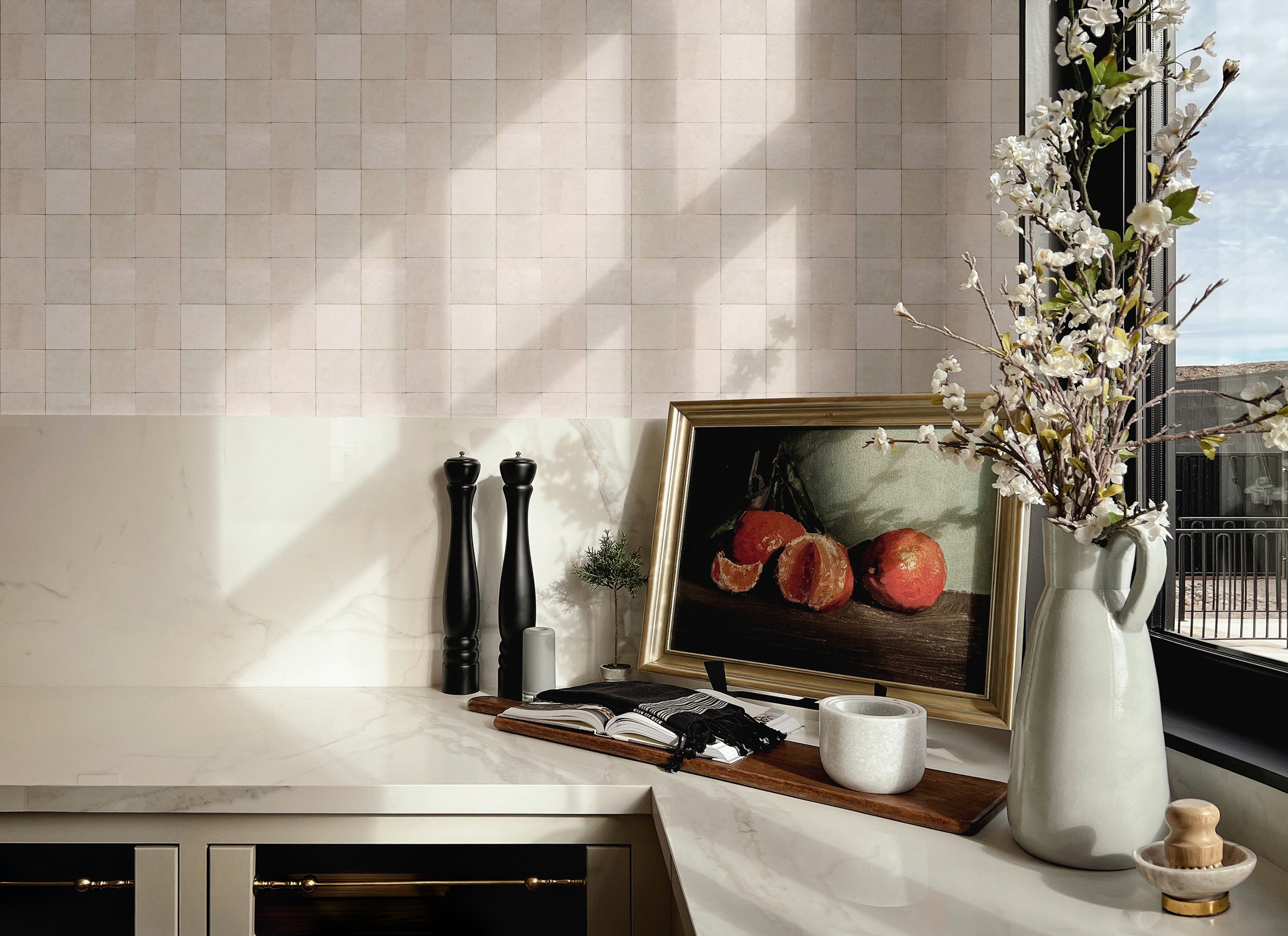 Zellige tile wallpaper used as a kitchen backsplash, styled with still life art, marble counter, and spring floral decor