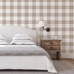 Light brown gingham wallpaper in bedroom with upholstered headboard and rustic nightstand