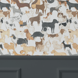 An elegant room with dark grey paneling halfway up the wall, topped with wallpaper displaying a lively assortment of painted dog illustrations in a repeat pattern.