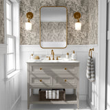 A well-lit bathroom interior with walls covered in a cream leaf pattern wallpaper that matches the previous image, completed with a wooden vanity with gold accents and a rectangular mirror.