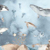 Ocean mural wallpaper designed for a child's room or nursery, showing a detailed and realistic sea life scene with creatures like orcas, whales, rays, and jellyfish, all set against a tranquil blue watercolor background. The mural offers a serene underwater world, perfect for a coastal-inspired kids' bedroom or a marine-themed play space.