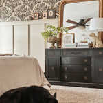  Same bedroom setup showing a sleeping black dog on a plush carpet, enhancing the homey feel. Olive branch wallpaper and black furniture remain consistent.