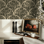 A stylish kitchen corner showcasing olive branch wallpaper as a backdrop. The scene includes marble countertops, a vase with blooming branches, salt and pepper mills, and an artwork of pomegranates.