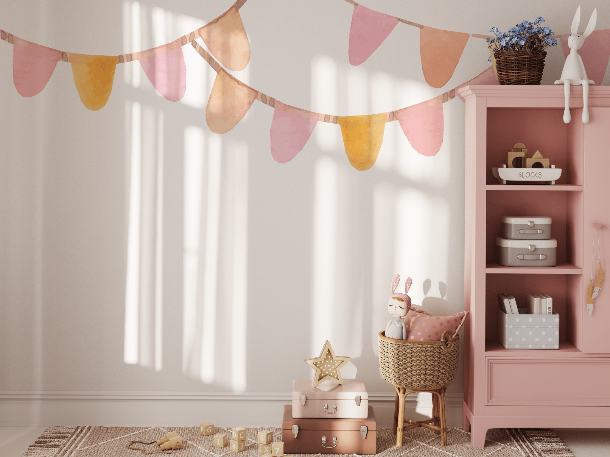 A playroom with a pastel bunting banner wall decal in pink, yellow, and orange. The decal hangs above a pink bookcase filled with toys and decor, including a stuffed rabbit and wicker basket, perfect for a playful, pastel-themed space.