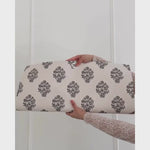 Unrolling cream background, dark charcoal grey block printed floral wallpaper.
