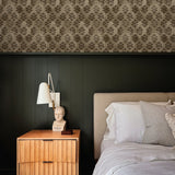 wallpaper above green wall treatment in bedroom with bed and side table