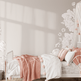 Girls' bedroom decorated with soft pink and white bedding, featuring large peony wall decals that create a whimsical and serene atmosphere. The floral decals add a charming touch to the cozy, dreamy room