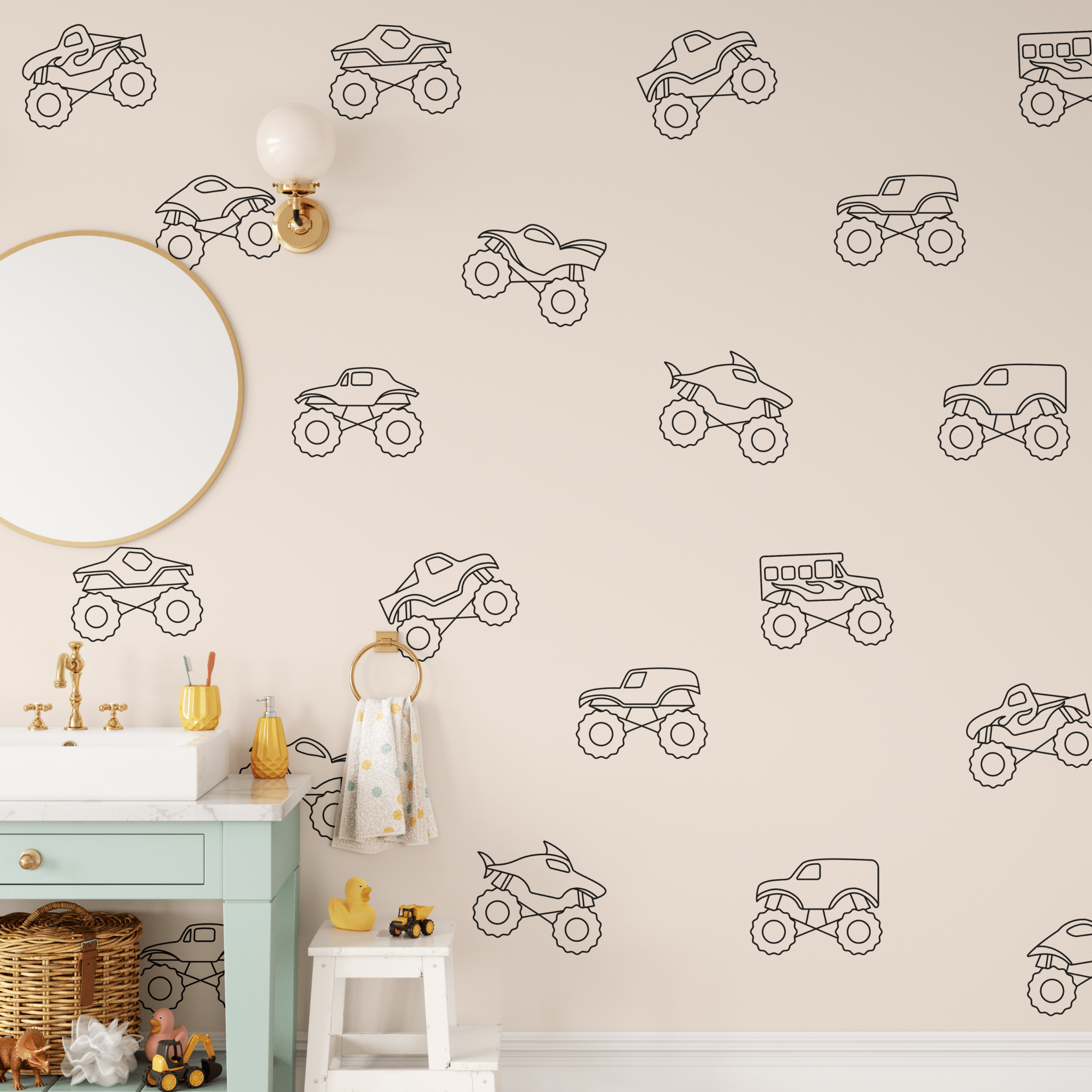 Playful black outline monster truck decals on a blush wall with a mint vanity, gold mirror, and toy trucks