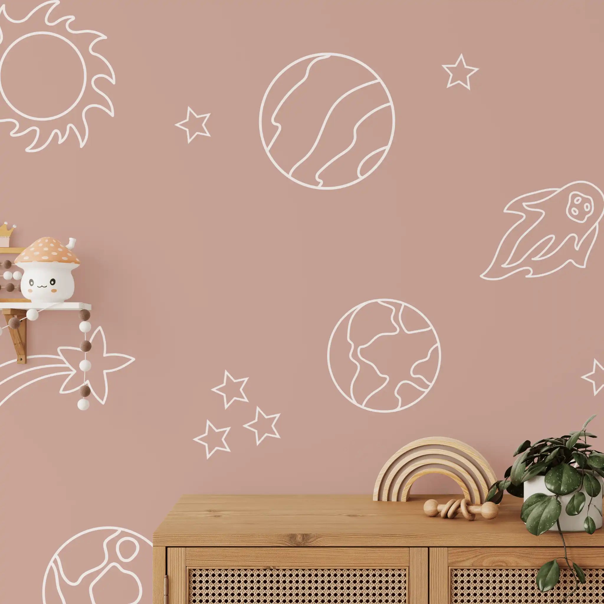 Close-up of white space decals on a dusty pink wall, including planets, stars, and a comet