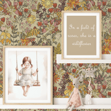 A girls' room with summertime floral wallpaper in bright colors, featuring framed artwork of a girl on a swing, a plush toy, and a quote, creating a cheerful and whimsical atmosphere.