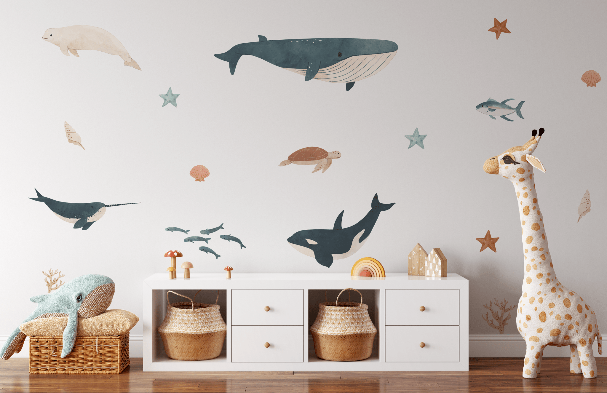 Children's room with whimsical ocean decals; plush dolphin, giraffe toy, and starfish adorn the space alongside wicker baskets.