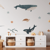 Children's room with whimsical ocean decals; plush dolphin, giraffe toy, and starfish adorn the space alongside wicker baskets.