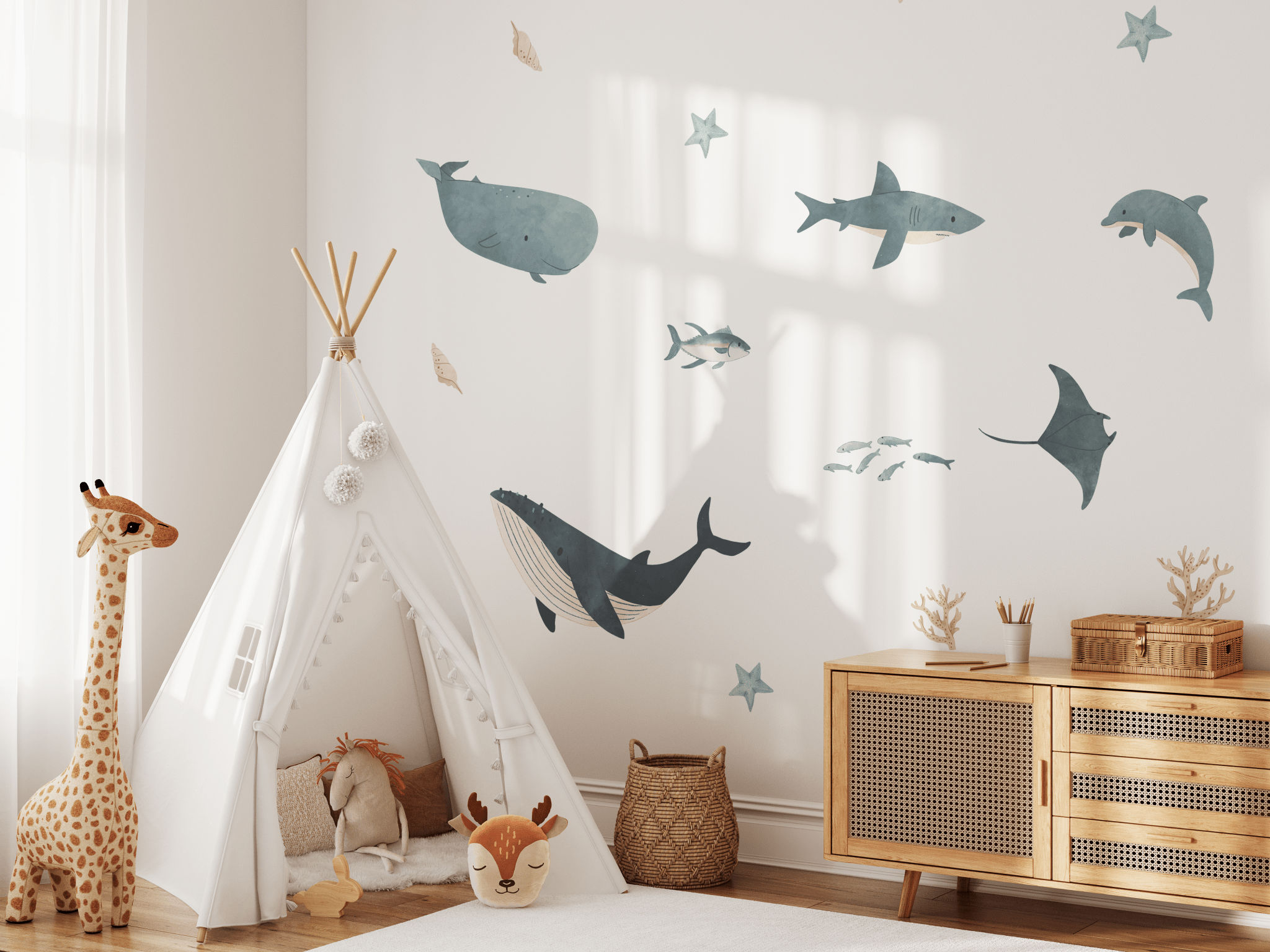 Bright, airy child's room with marine wall decals, a teepee play tent, and a tall plush giraffe next to a modern wooden dresser