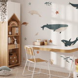 Study corner in a kid's room decorated with charming sea creature decals, accompanied by a stuffed dolphin and warm wooden furniture.