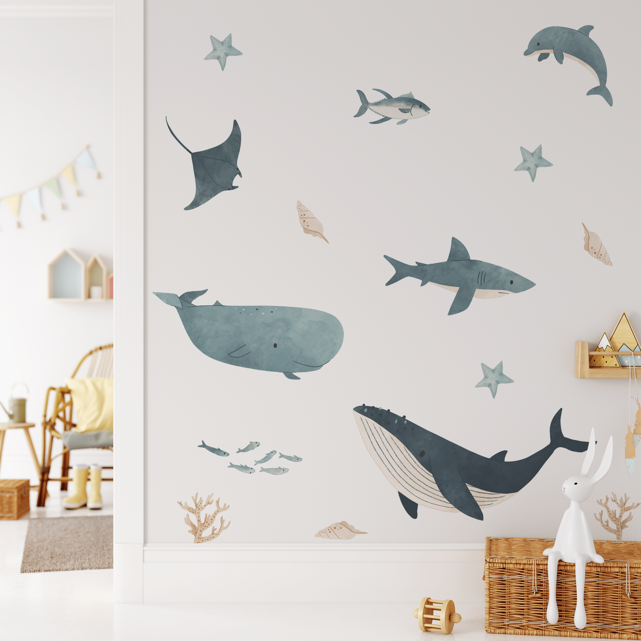 Playful ocean-themed wall stickers in a children's room featuring sea stars and fish, complemented by a white rabbit figurine and wicker baskets.