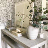 Peel and Stick wallpaper behind a decorative table with Potted plant and books