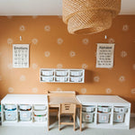 Children's learning space with terracotta walls adorned with sunburst decals, educational posters, and organized storage bins