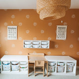 Children's learning space with terracotta walls adorned with sunburst decals, educational posters, and organized storage bins