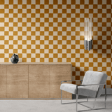 Modern interior with a burnt orange and cream checkered wallpaper, wooden sideboard, teal vase, and a grey armchair
