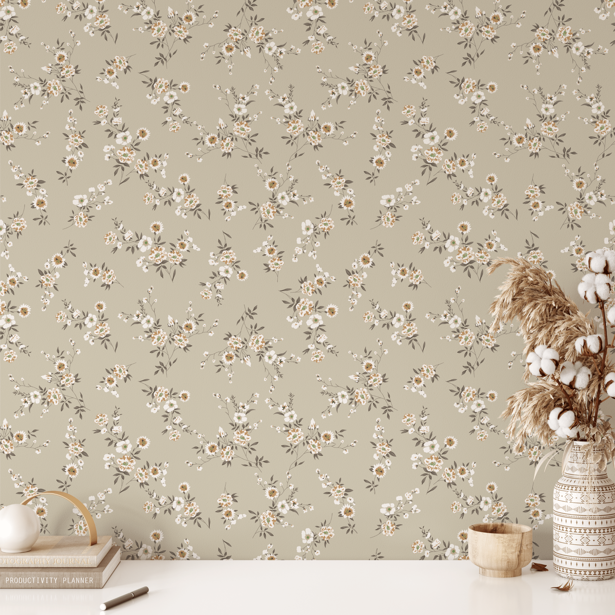 Workspace with beige floral wallpaper, white desk, and dried flowers in a woven vase.