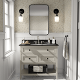 A bathroom with beige floral wallpaper, white vanity with black countertop, rectangular mirror, and black sconce lights.