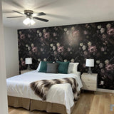 Moody Dark Floral wallpaper in a room with ceiling fan, white bedding, and light wood flooring