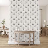 A stylish room with a wall covered in floral blueprint peel and stick removable wallpaper. A wooden table with white vases and a coral piece sits in front, and a dining area is subtly visible in the background