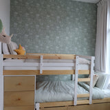 Bright and airy child's bedroom with pine bunk bed, forest green floral wallpaper, and a window draped with sheer white curtains.