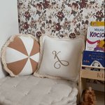 A cozy reading nook with a large cushioned floor seat, decorative pillows, and a floral wallpaper featuring maroon and taupe flowers