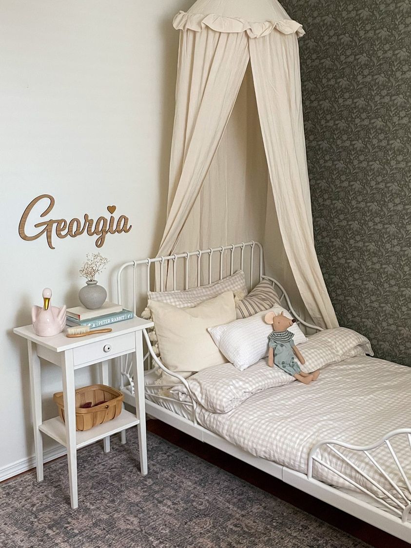 Simplistic child's room with neutral decor and dark green peel and stick wallpaper